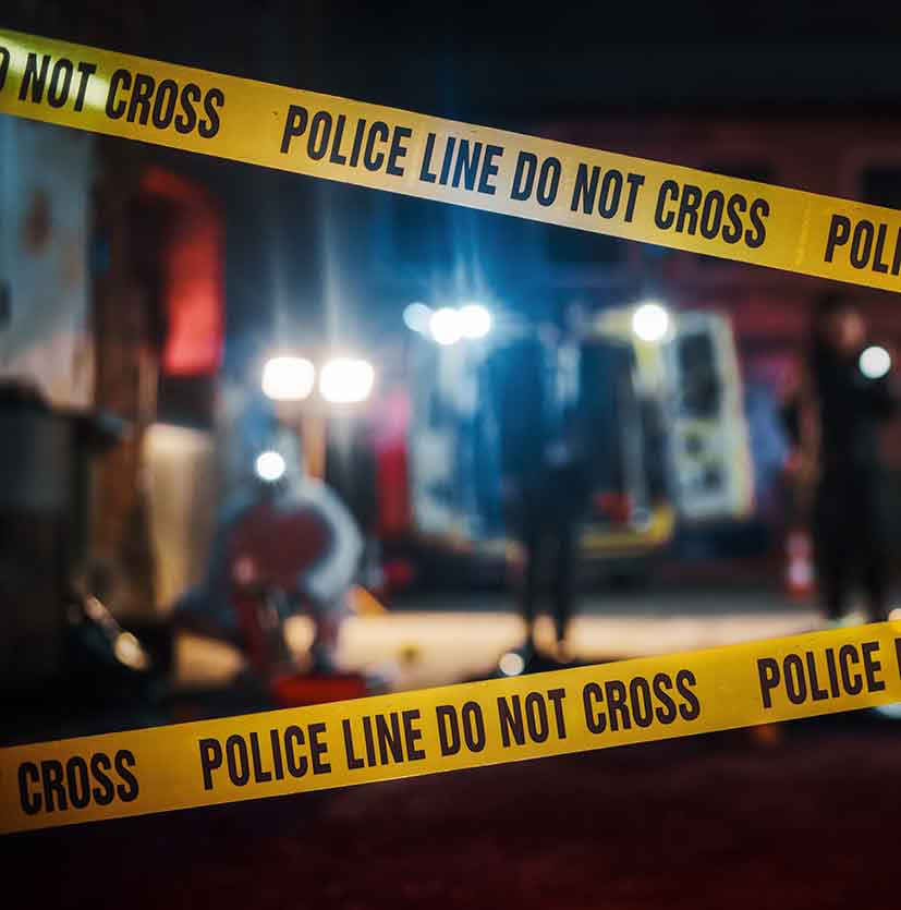 Crime scene tape in foreground and police crime scene in background