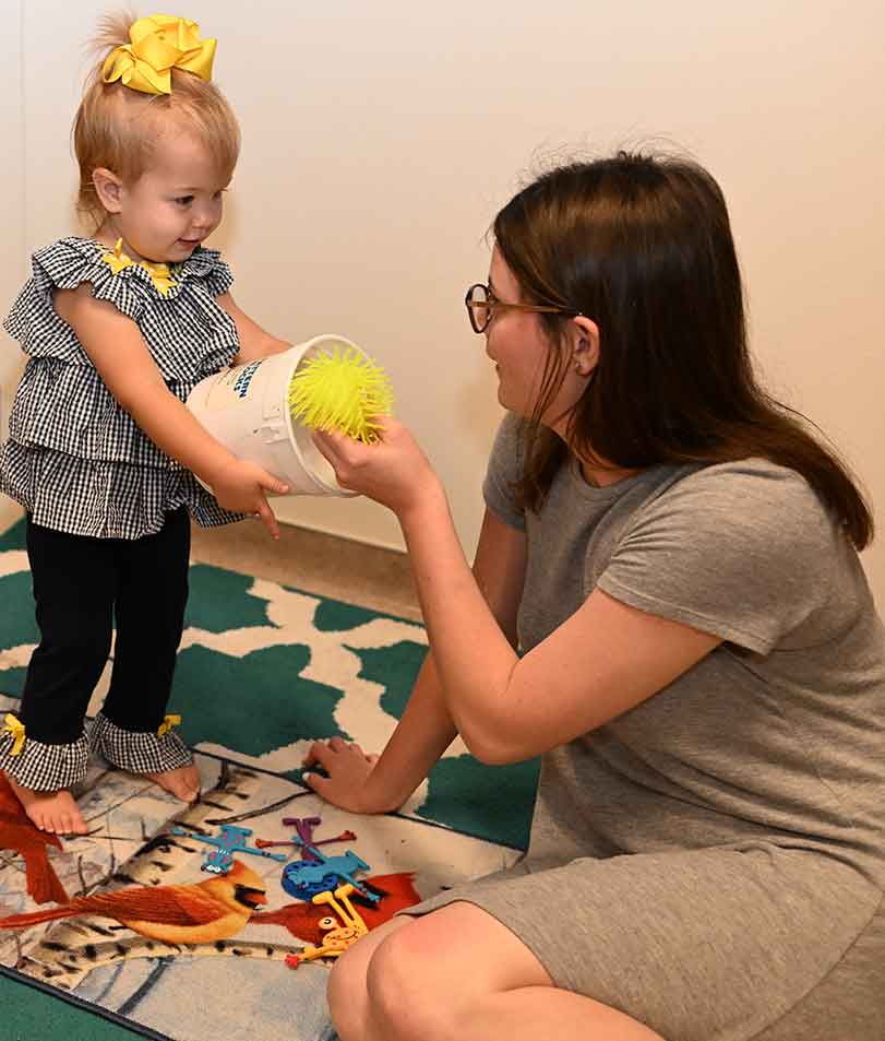 Student and toddler playing together with toys