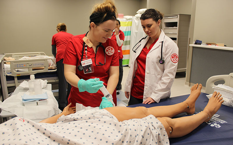 Two student nurses practicing on a manikin