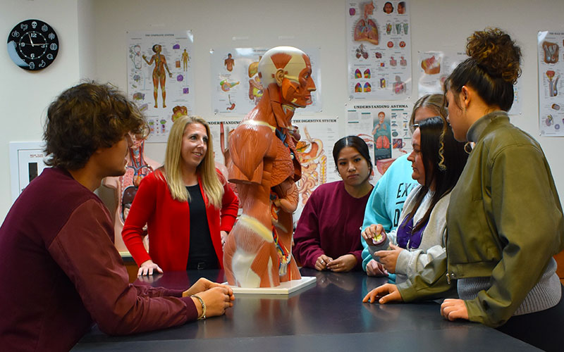 a group of students around a table studying the anatomy of the human body