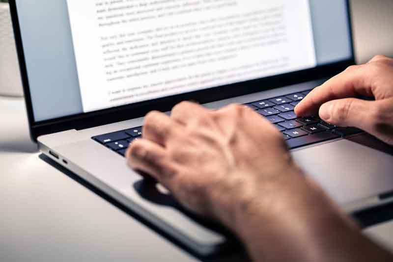 Person typing a word document on a laptop